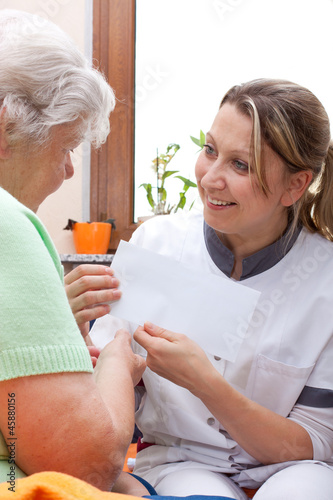 Photo: Pflegerin überreicht Patientin einen umschlag Pflegerin überreicht Patientin einen umschlag