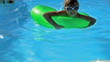 Children sitting on inflatable ring in swimming pool.