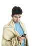 Young man wrapped in a plaid looking at his smartphone