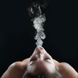 Woman smoking against dark background. Studio fashion photo.