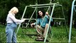 Мужина и беременная женщина отдыхают на детских качелях