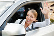 woman sitting in the car and waving her hand