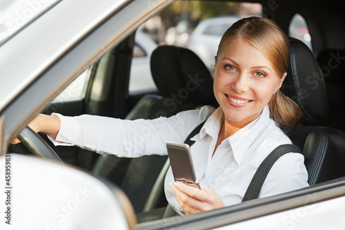 Photo: woman sitting in the car and holding mobile phone woman sitting in the car and holding mobile phone