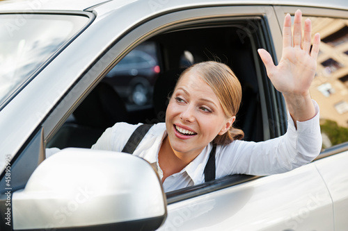 Photo: woman sitting in the car and waving her hand woman sitting in the car and waving her hand