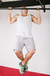 Closeup of young strong teenage athlete doing pull-up on horizon