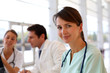 Photo: Attractive nurse working in hospital, people in background Attractive nurse working in hospital, people in background