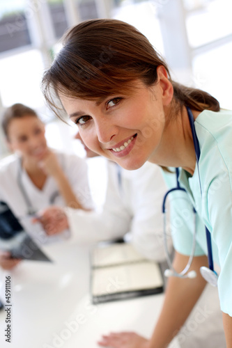 Photo: Attractive nurse working in hospital, people in background Attractive nurse working in hospital, people in background