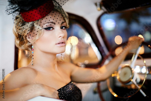 Photo: beautiful fashion girl in retro style sitting in old car beautiful fashion girl in retro style sitting in old car