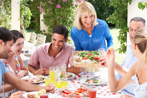 Photo: Group Of Young And Senior Couples Enjoying Family Meal Group Of Young And Senior Couples Enjoying Family Meal