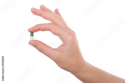 Photo: Hand holding a capsule or pill isolated on white Hand holding a capsule or pill isolated on white