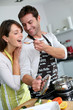Man preparing dinner and making her wife taste the food