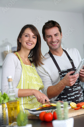 Photo: Couple in home kitchen using electronic tablet Couple in home kitchen using electronic tablet