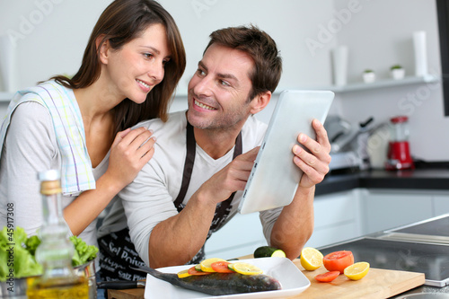 Photo: Couple in home kitchen using electronic tablet Couple in home kitchen using electronic tablet