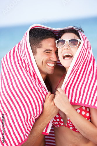 Photo: Couple Sheltering From Sun On Beach Holiday Couple Sheltering From Sun On Beach Holiday