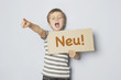 Kind hält Schild mit Typo Neu
