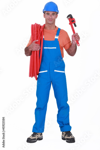 Photo: Tradesman holding corrugated tubing and a pipe wrench Tradesman holding corrugated tubing and a pipe wrench