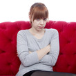 young beautiful red haired girl on red sofa is offended