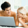Cheerful couple with laptop, at home