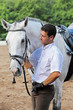 Jockey in gloves hug horse on hippodrome