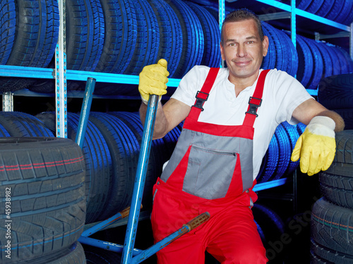 Photo: Car mechanic stores winter tires in a tire warehouse Car mechanic stores winter tires in a tire warehouse