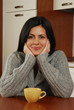 Foto: Joven mujer bebiendo una taza de tè o café en casa. Joven mujer bebiendo una taza de tè o café en casa.