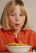 Niña rubia feliz comiendo pasta,almorzando,cenando.