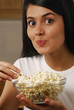 Joven mujer comiendo palomitas de maíz.
