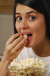 Joven mujer comiendo palomitas de maíz.