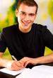 Young smiling man writing, outdoor