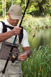 man watching his fishing rod in front of a river