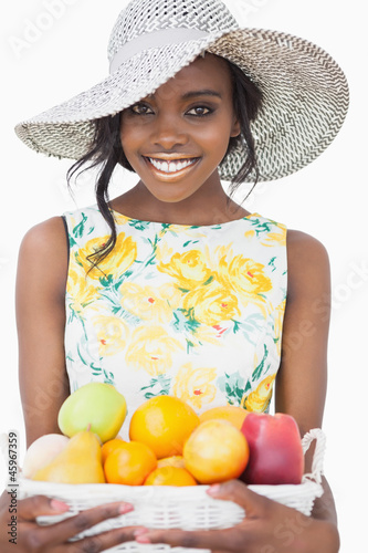 Photo: Woman standing holding a fruit basket Woman standing holding a fruit basket