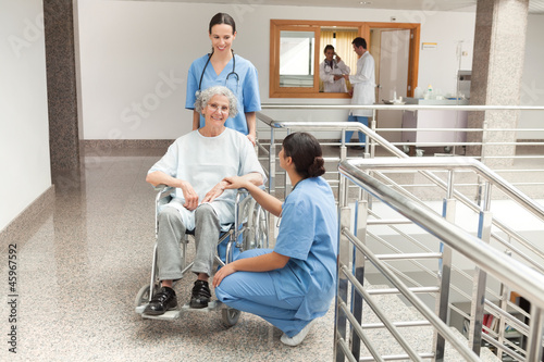 Photo: Two nurses looking after old women sitting in wheelchair Two nurses looking after old women sitting in wheelchair