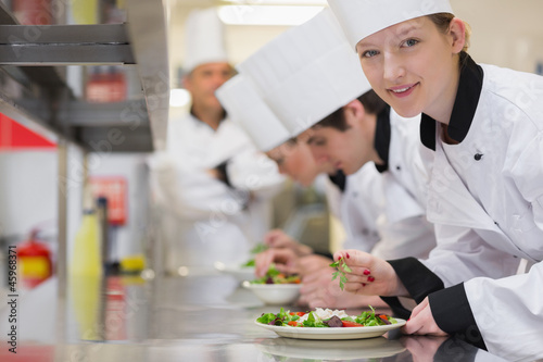Photo: Happy chef looking up from preparing salad Happy chef looking up from preparing salad