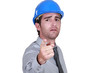 Man with a hard hat pointing at camera.