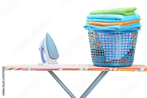 Photo: Studio shot of iron and laundry basket full of clothes on ironin Studio shot of iron and laundry basket full of clothes on ironin