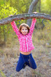 children girl swinging in a trunk in pine forest