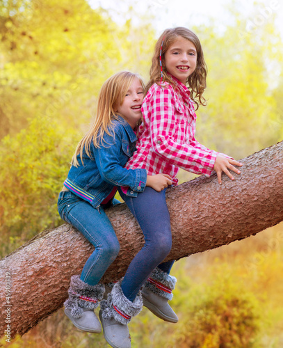 Photo: children friends girls climbing to a pine tree trunk children friends girls climbing to a pine tree trunk
