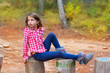 children girl relaxed on a tree trunk in the forest