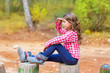 Kid girl sitting in forest trunk looking far away