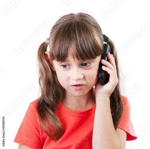 Photo: Little girl with a phone on gray background Little girl with a phone on gray background