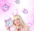 Beautiful young girl in bunny ears holding pink clock