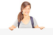 School girl with backpack posing behind white panel