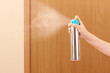 Sprayed air freshener in hand on room background