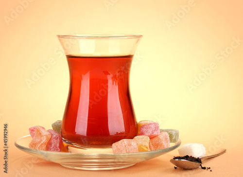 Photo: glass of Turkish tea and rahat Delight, on beige background glass of Turkish tea and rahat Delight, on beige background