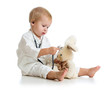 Photo: Adorable child with clothes of doctor and teddy bear over white Adorable child with clothes of doctor and teddy bear over white