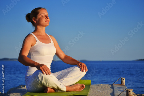 Photo: Young woman during yoga meditation on the beach Young woman during yoga meditation on the beach
