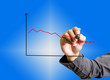 businessman drawing graph of cost reduction