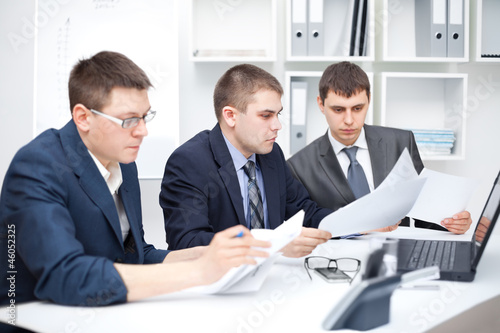 Photo: Team of young business men doing some paperwork together Team of young business men doing some paperwork together