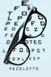 eyeglasses over a blurry eye chart