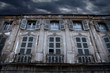 Old house with gray shutters and thunder clouds in the sky.